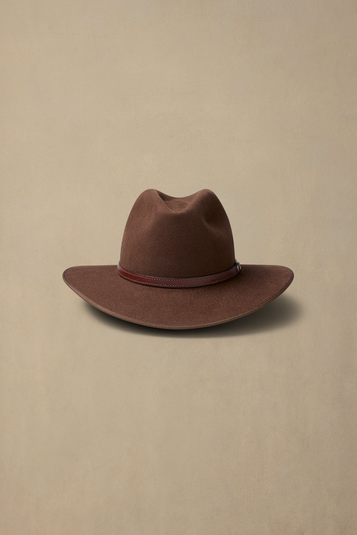 Brown fur felt Coober Pedy cowboy hat with burgundy leather band on neutral background