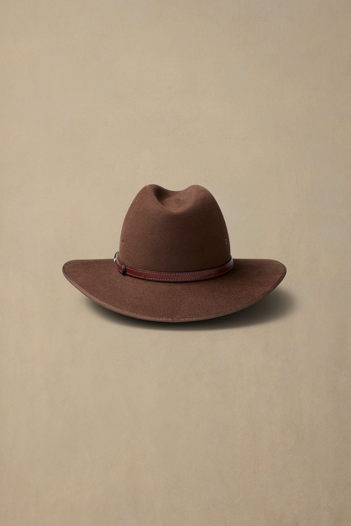 Brown fur felt Coober Pedy cowboy hat with leather band on neutral background