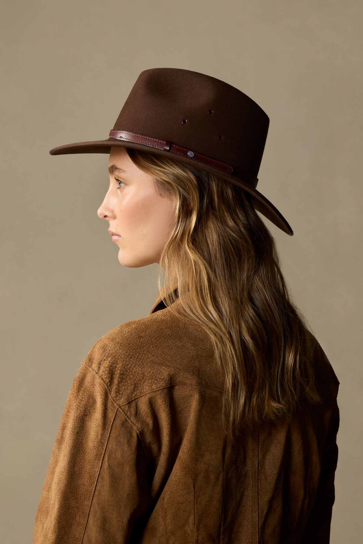 Brown felt Coober Pedy cowboy hat with leather band, shown on model in profile view against neutral background
