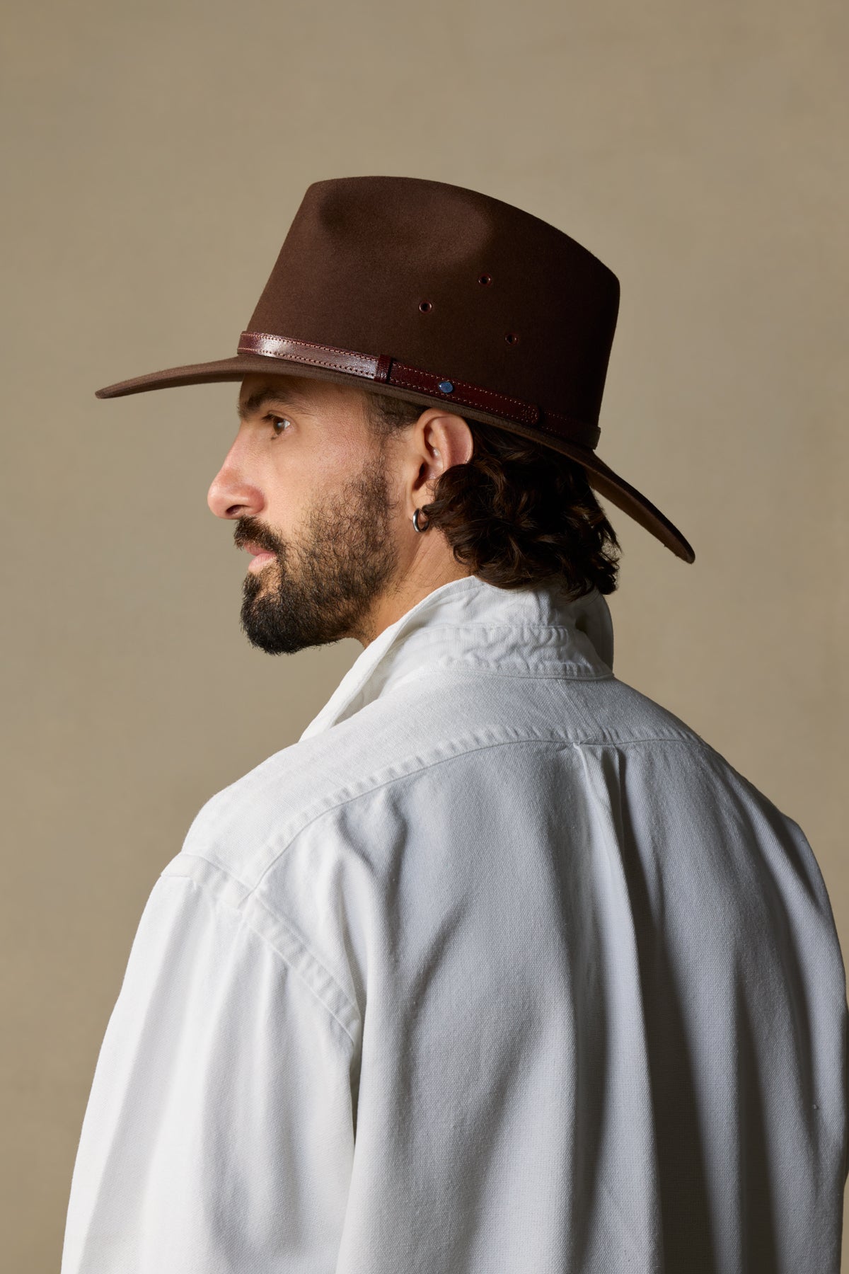 Brown fur felt cowboy hat with burgundy band, shown from side profile on bearded man wearing light gray shirt