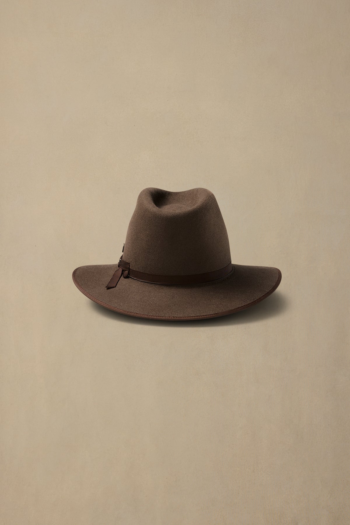 Mid brown rabbit fur felt hat with leather band detail on neutral background