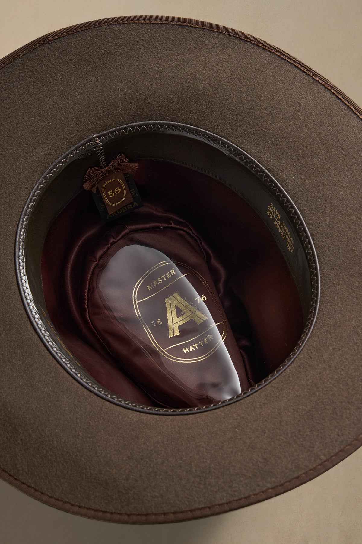 R.M. mid brown fur felt hat displayed inside gray packaging with burgundy silk lining visible