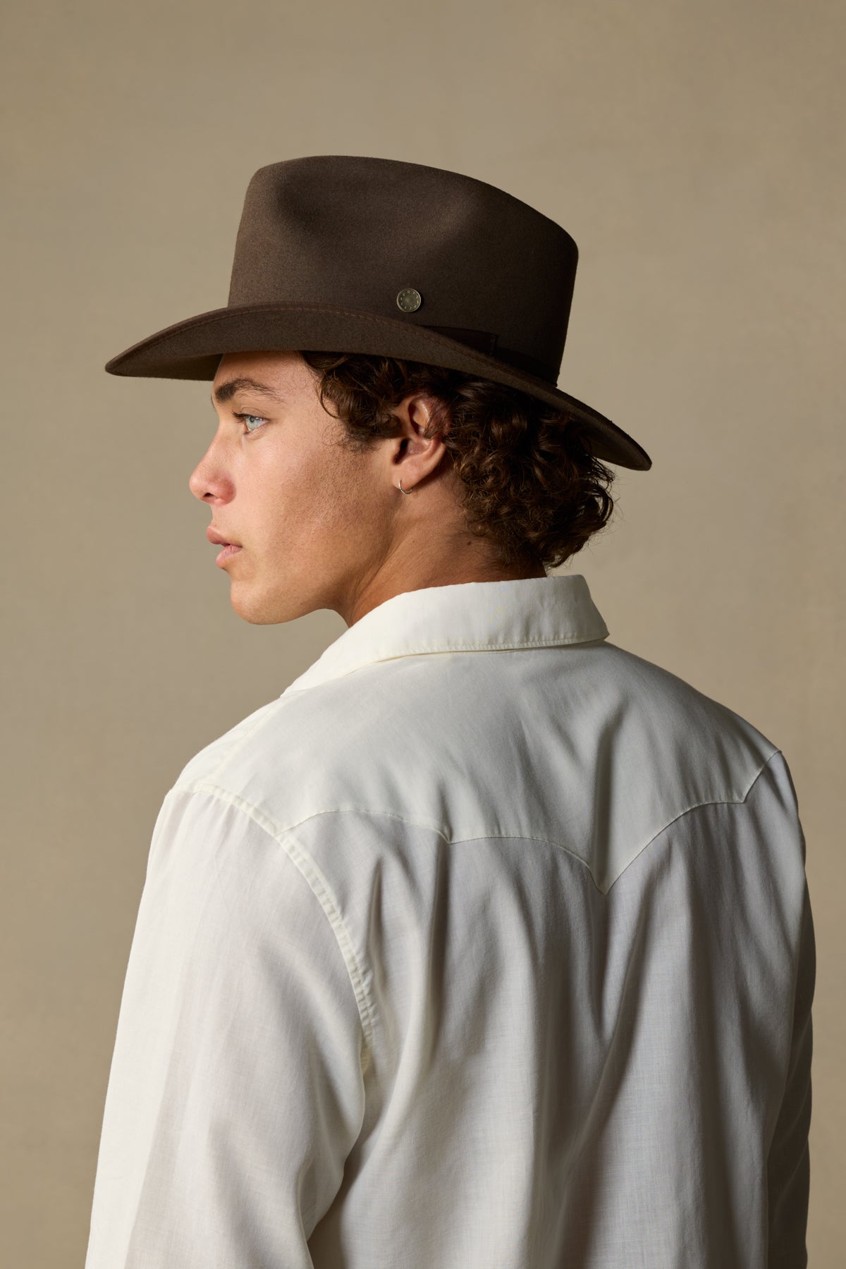 Mid brown rabbit fur cowboy hat worn by model in profile against neutral background