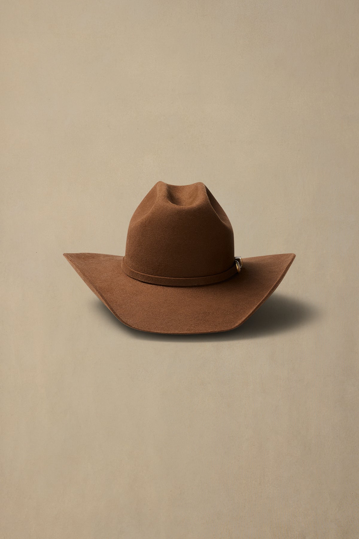 Brown fur felt cowboy hat with cattleman crown and wide brim on neutral background