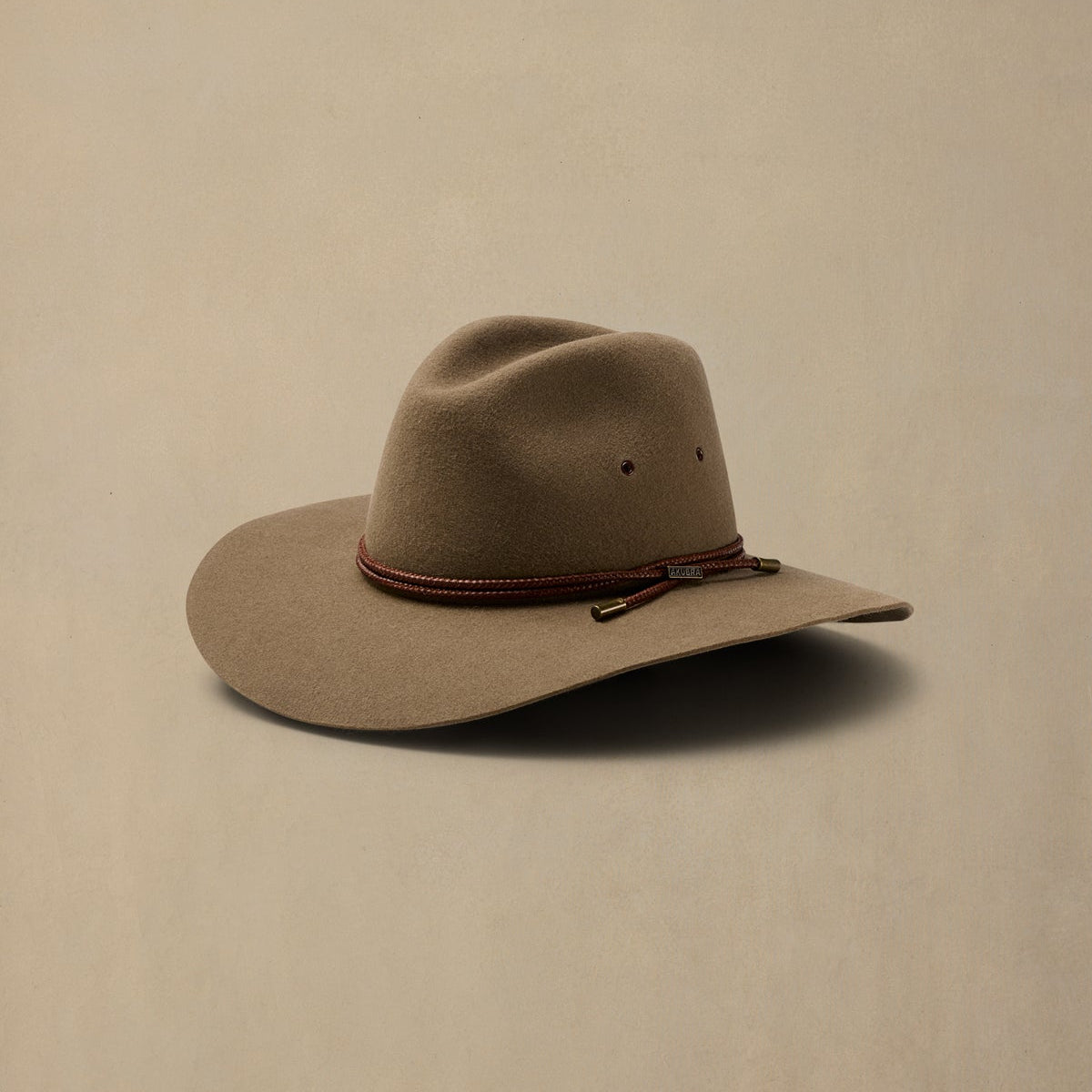 Tan rabbit fur cowboy hat with burgundy braided band against neutral background