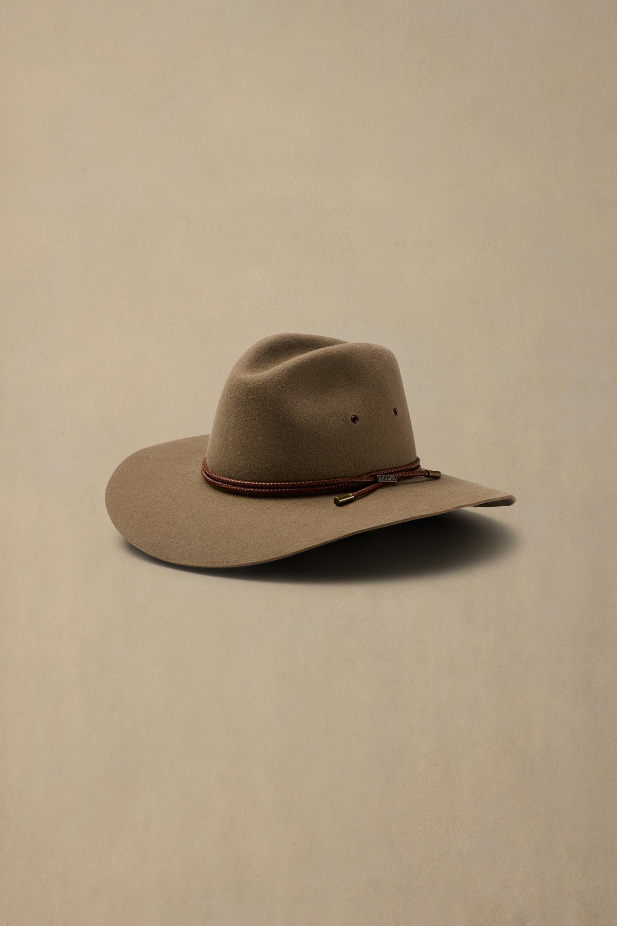Tan rabbit fur cowboy hat with burgundy braided band on neutral background