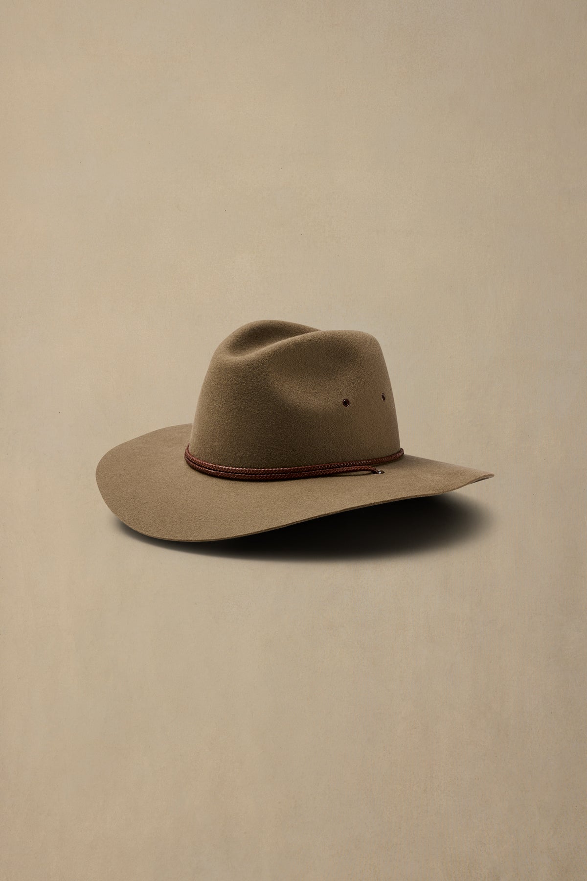 Tan rabbit fur Traveller hat with burgundy cord band on neutral background