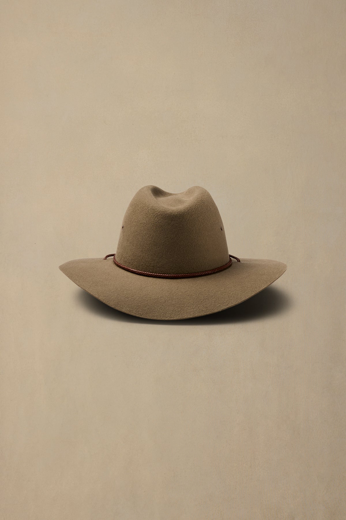 Tan rabbit fur cowboy hat with burgundy chin cord on neutral background, front view