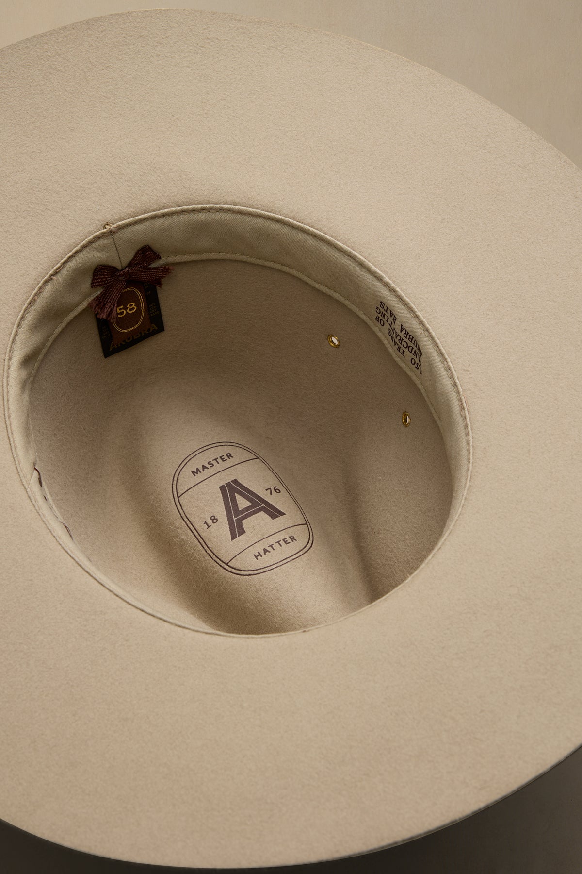 Cream-colored felt Traveller hat interior view showing Master Hatter label and burgundy size tag 58