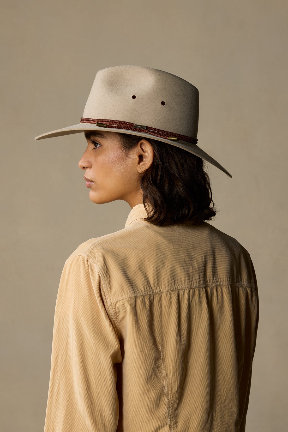 Cream-colored rabbit fur felt cowboy hat with burgundy band, shown on model wearing tan shirt against neutral background