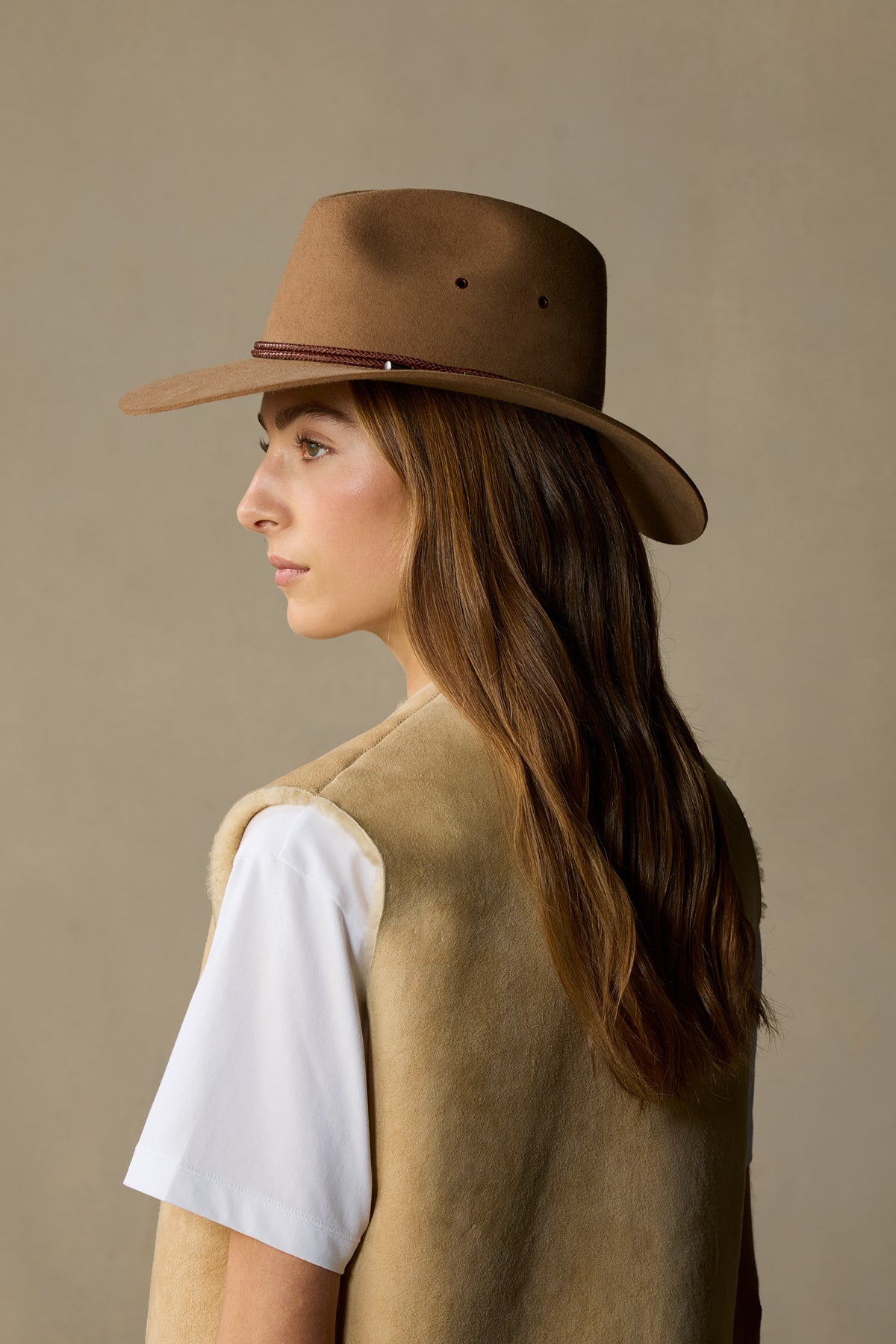 Woman wearing spice brown rabbit fur traveller hat with burgundy band, side profile view against neutral background