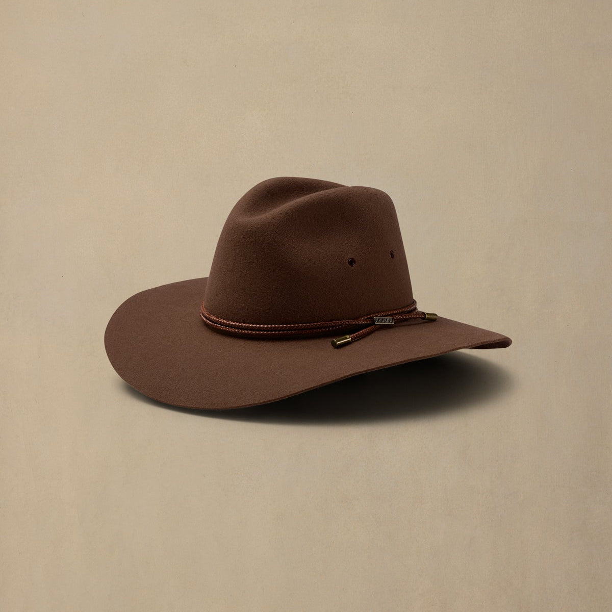 Brown rabbit fur cowboy hat with rope band detail against neutral background