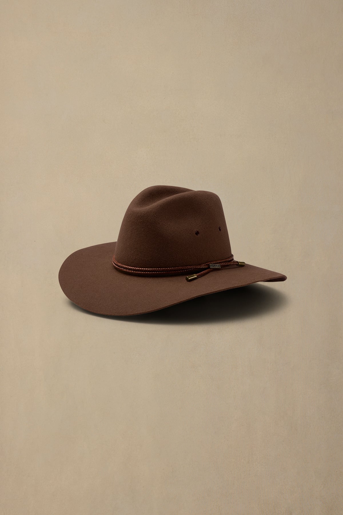 Brown rabbit fur felt cowboy hat with braided band on cream background