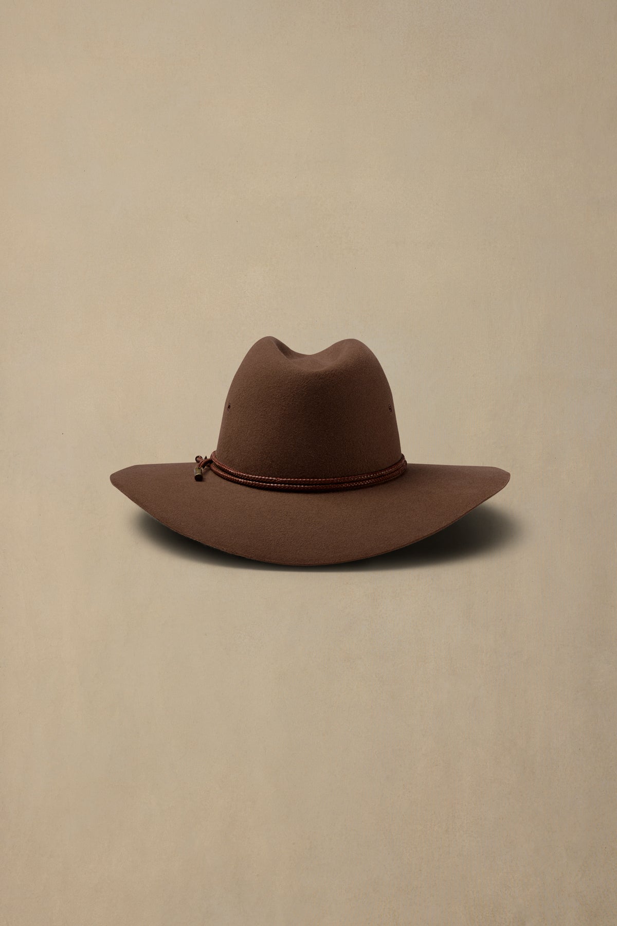 Brown rabbit fur cowboy hat with decorative beaded band on cream background
