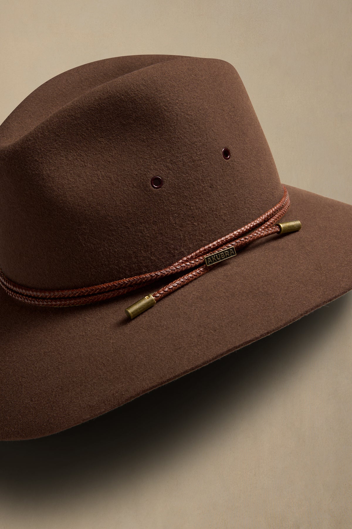Brown fur felt traveller hat with braided cord band and brass accents, angled side view