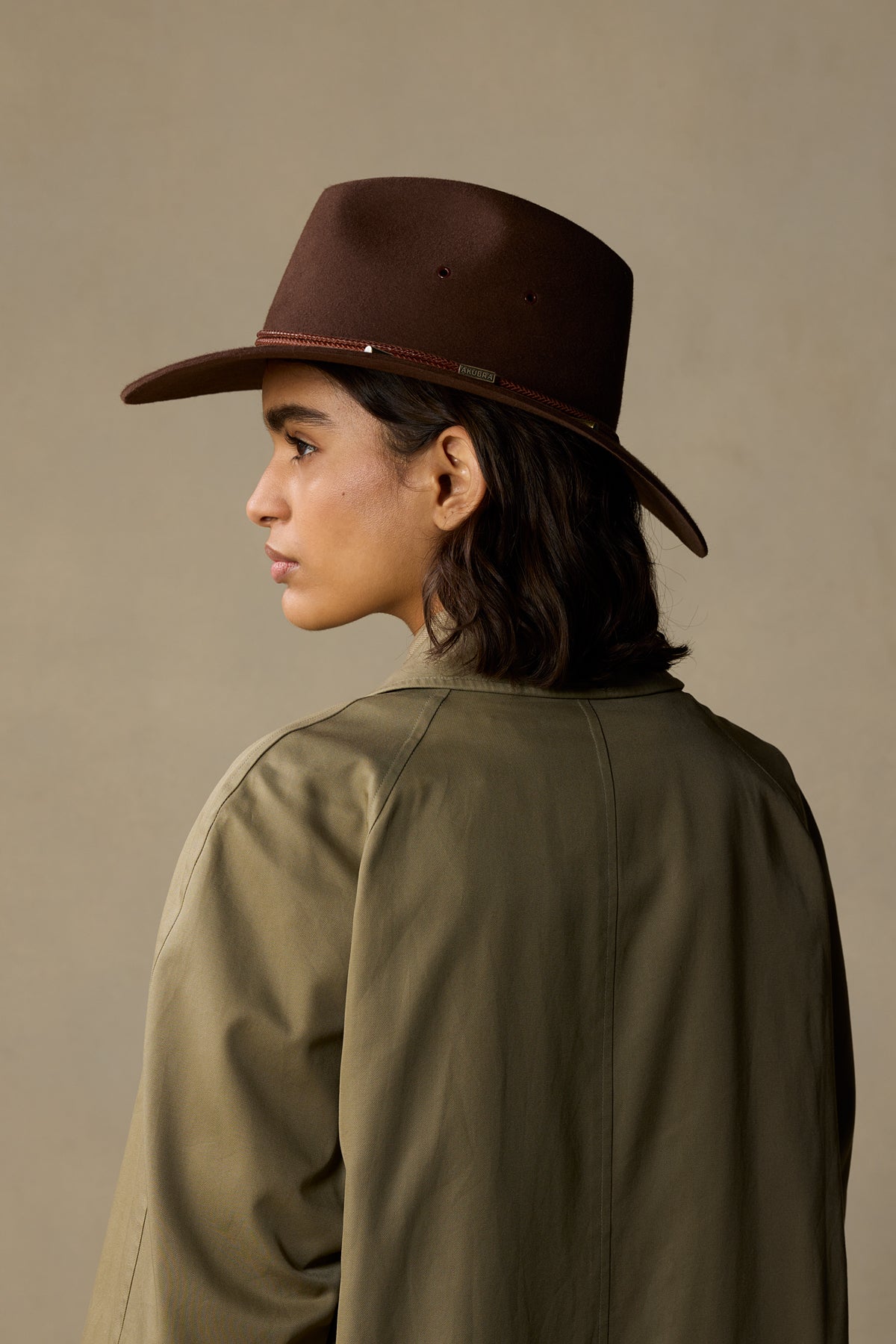 Brown fur felt traveller hat with braided trim on model wearing olive jacket, profile view