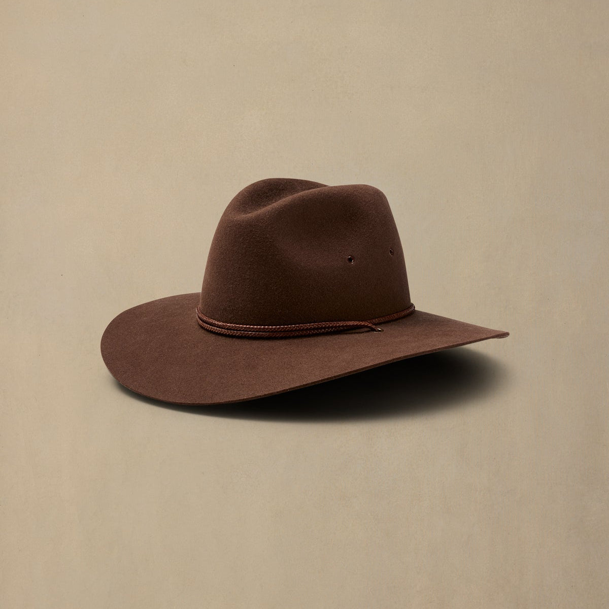 Brown rabbit fur felt cowboy hat with rope band detail on neutral background
