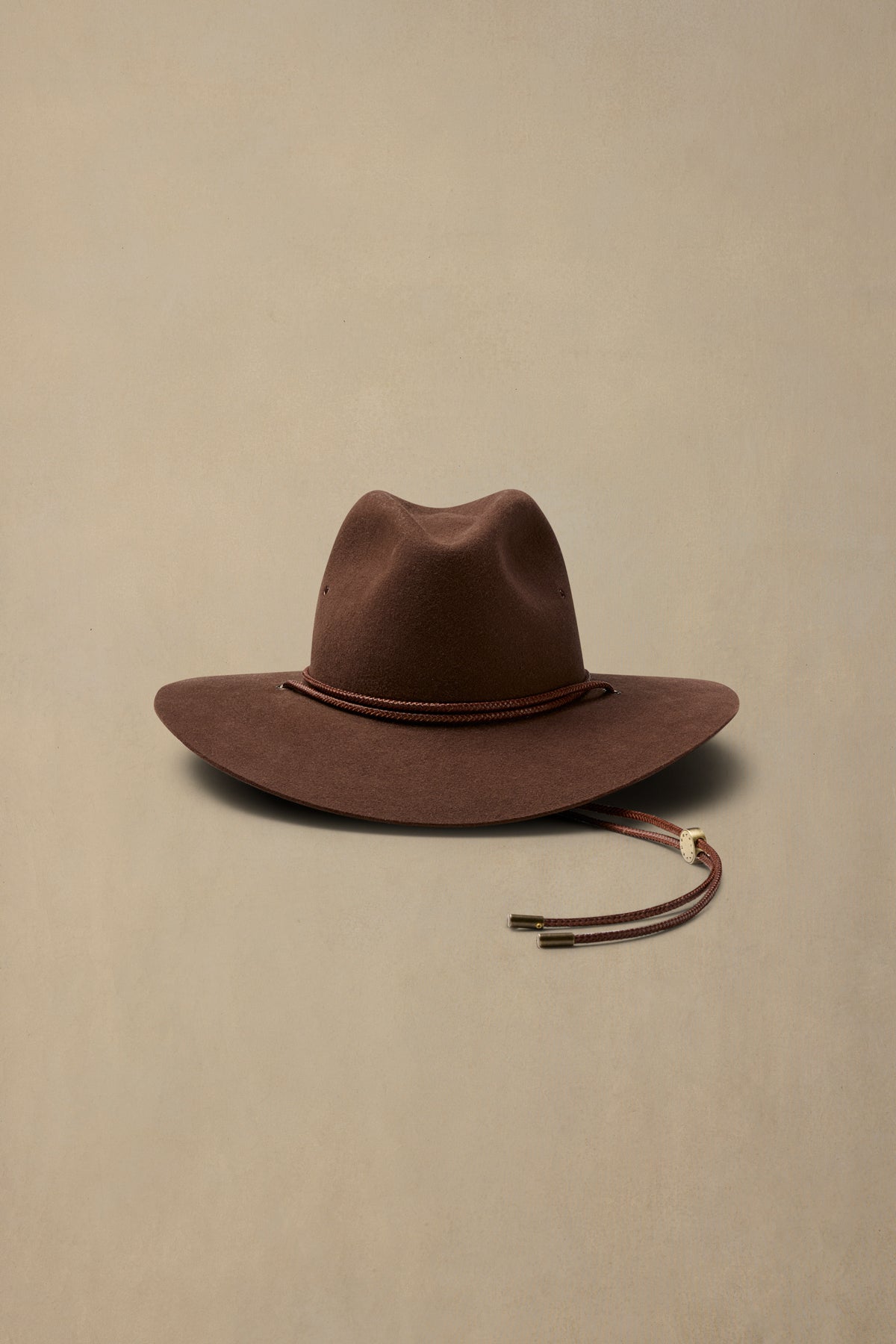 Brown rabbit fur traveller hat with cord chin strap on neutral background