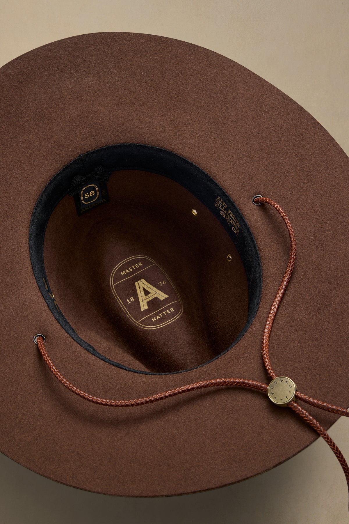 Brown rabbit fur felt cowboy hat with chin strap viewed from above, showing interior label and size 56 marking