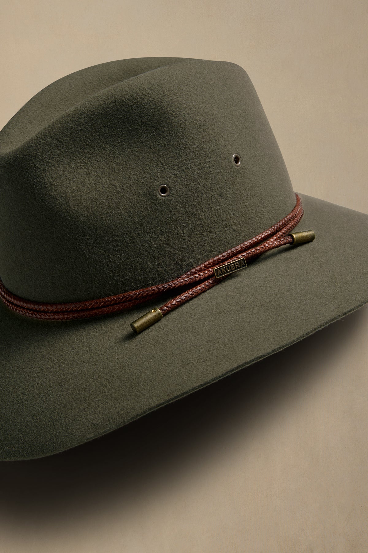 Fern green rabbit fur felt traveller hat with burgundy braided cord and brass accents, displayed at angle on neutral background