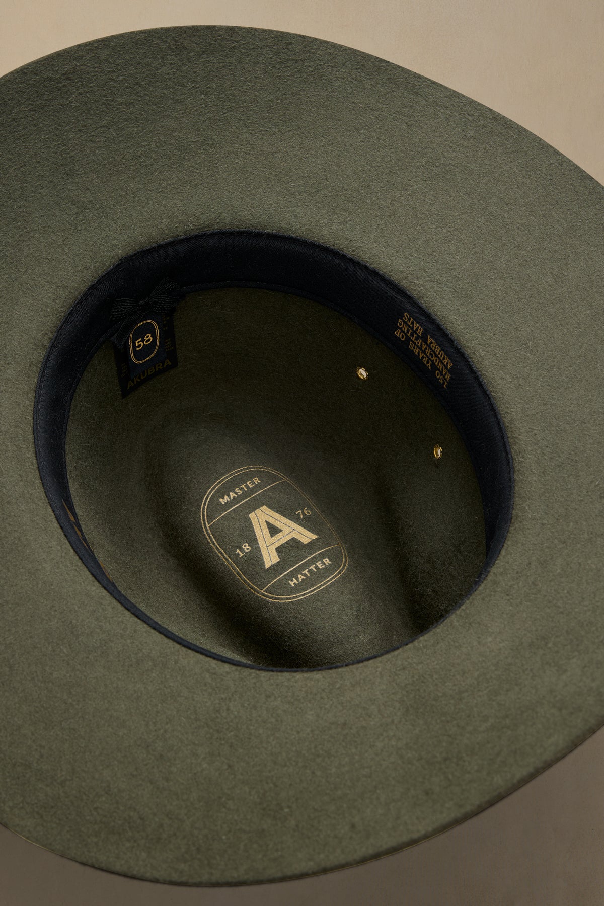 Fern green felt Traveller hat viewed from above, showing interior black band with gold "A" badge and size 58 label against neutral background