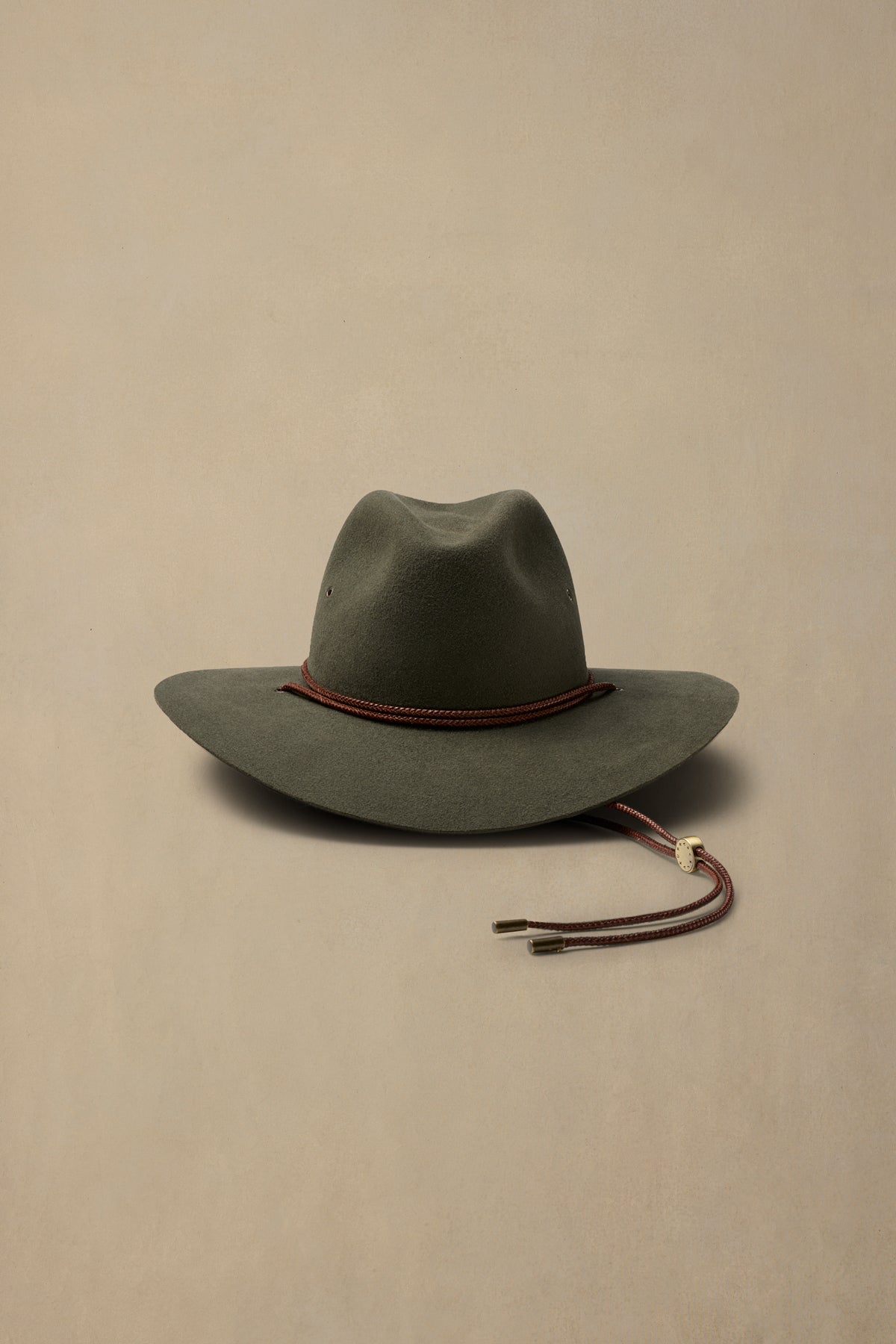 Sage green rabbit fur felt cowboy hat with burgundy cord and chin strap on neutral background
