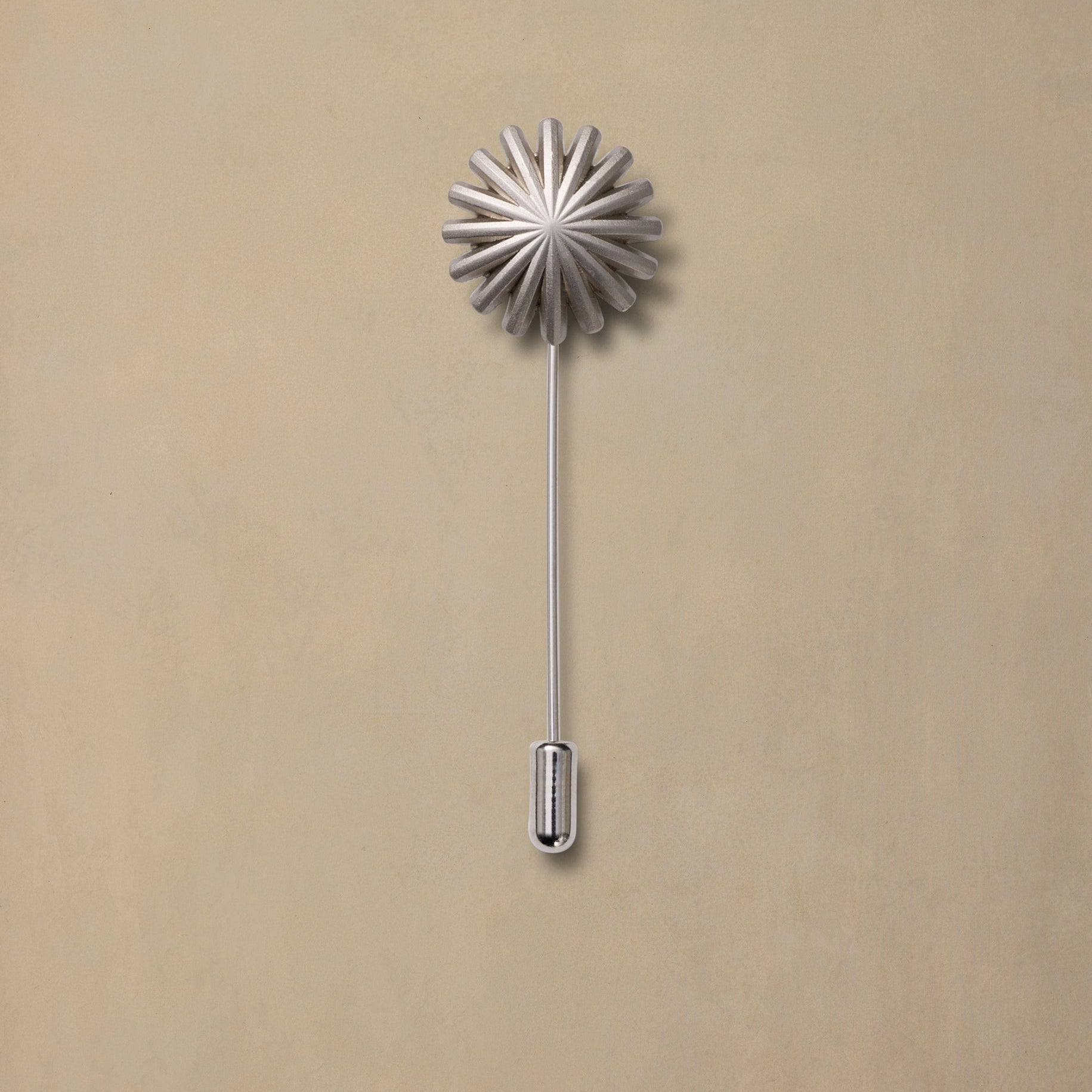 Hotrod Pewter decorative pin with radiating fan-shaped top and long stem on neutral beige background