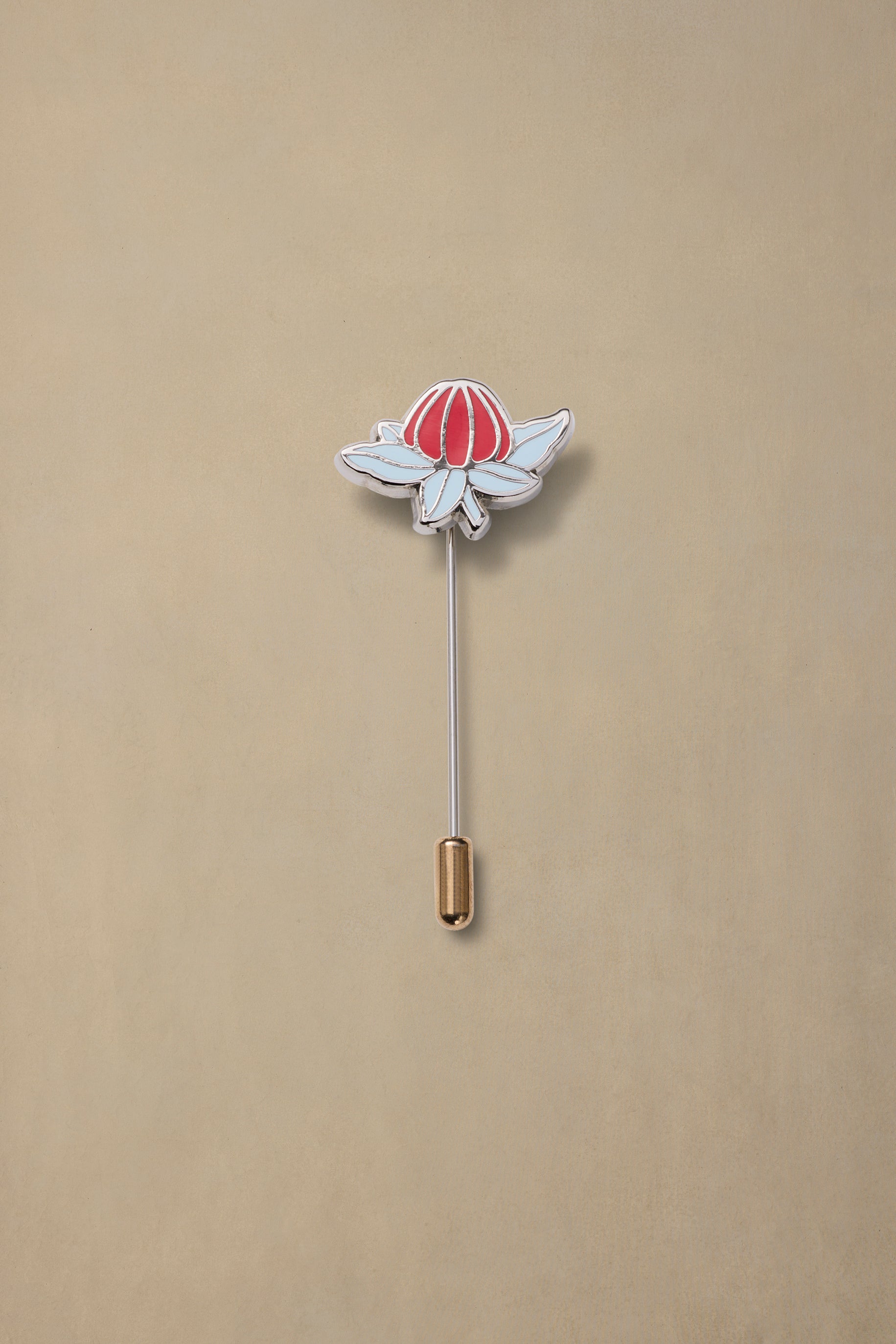 Red and white enamel flower pin with gold backing on beige background