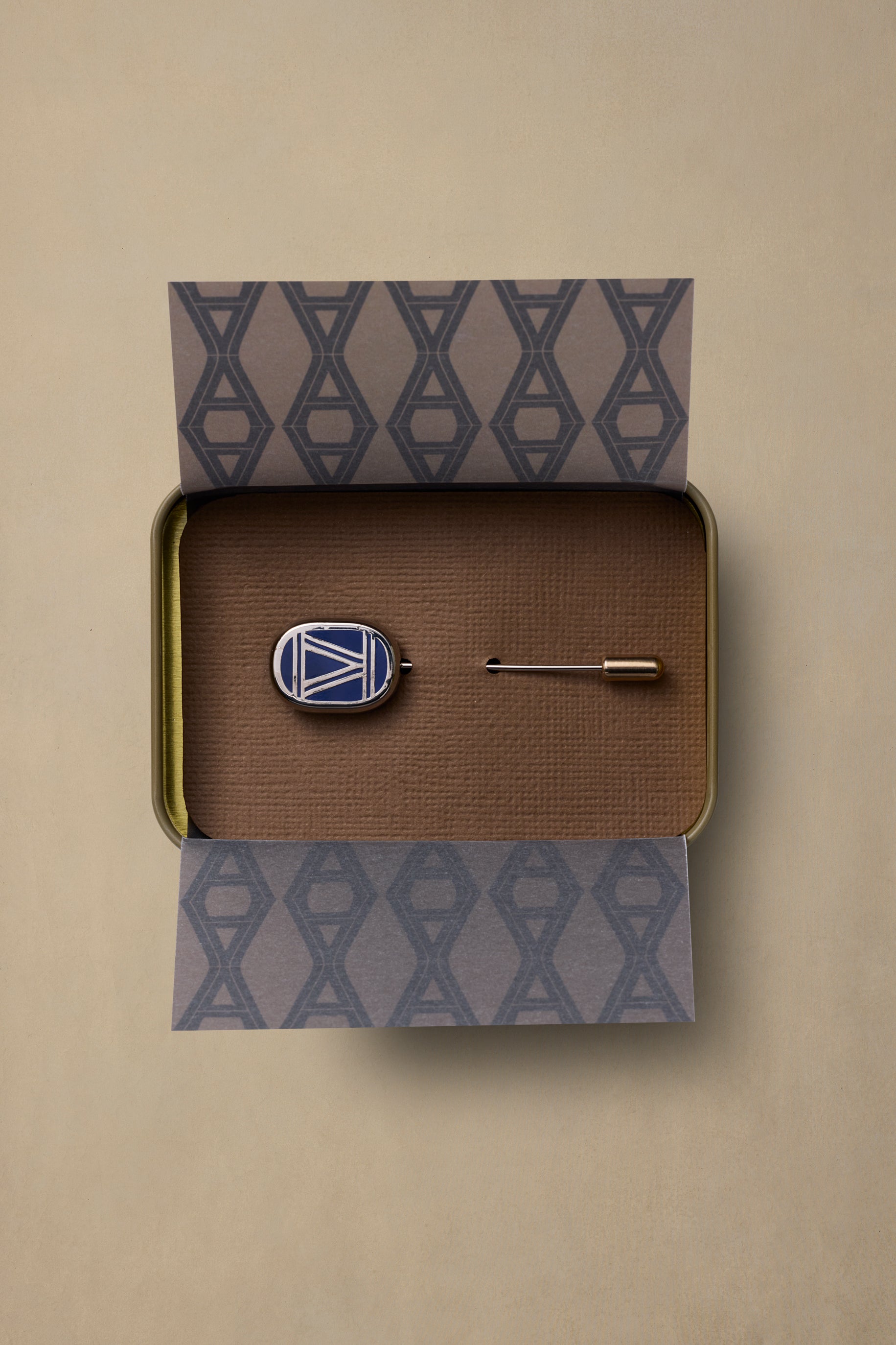 VIC State enamel pin with geometric design in navy and white, displayed in branded gift box with brown interior and patterned packaging