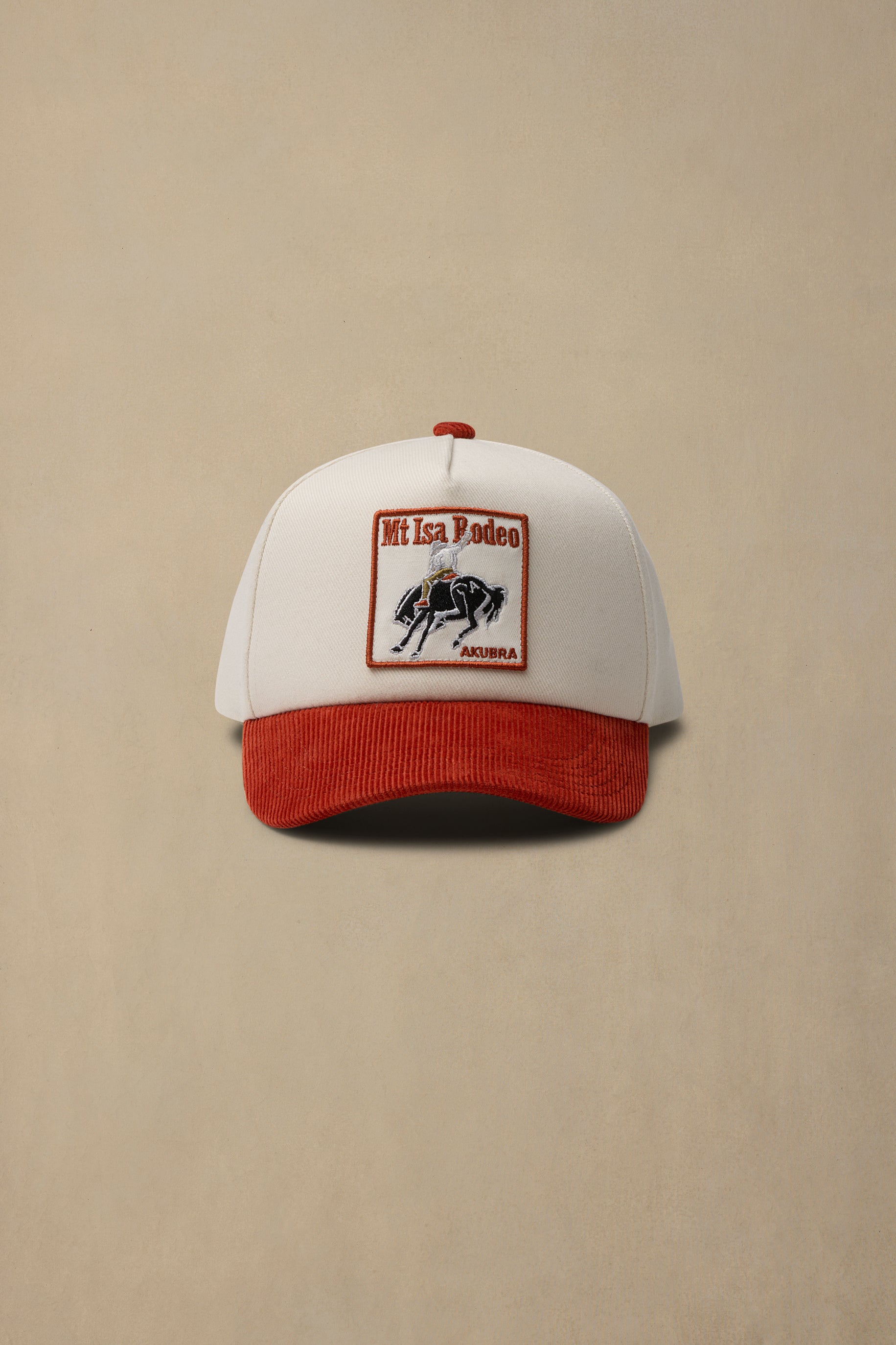 A white and red baseball cap with a rectangular embroidered patch on the front that reads 'Mt Isa Rodeo' and 'Arizona' with a black horse graphic, shown against a plain beige background.