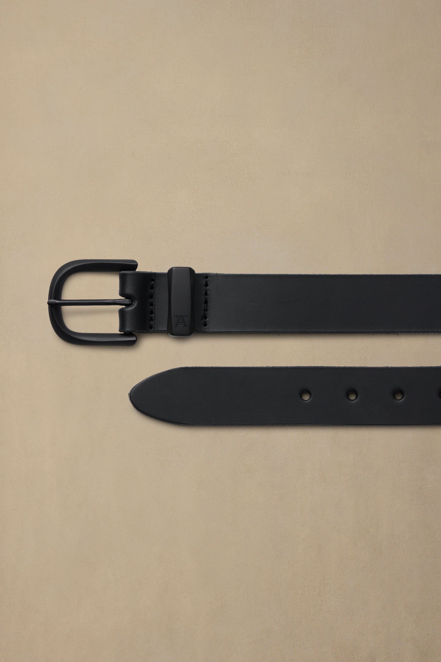 Black leather belt with metal buckle displayed flat on neutral background showing adjustable sizing holes