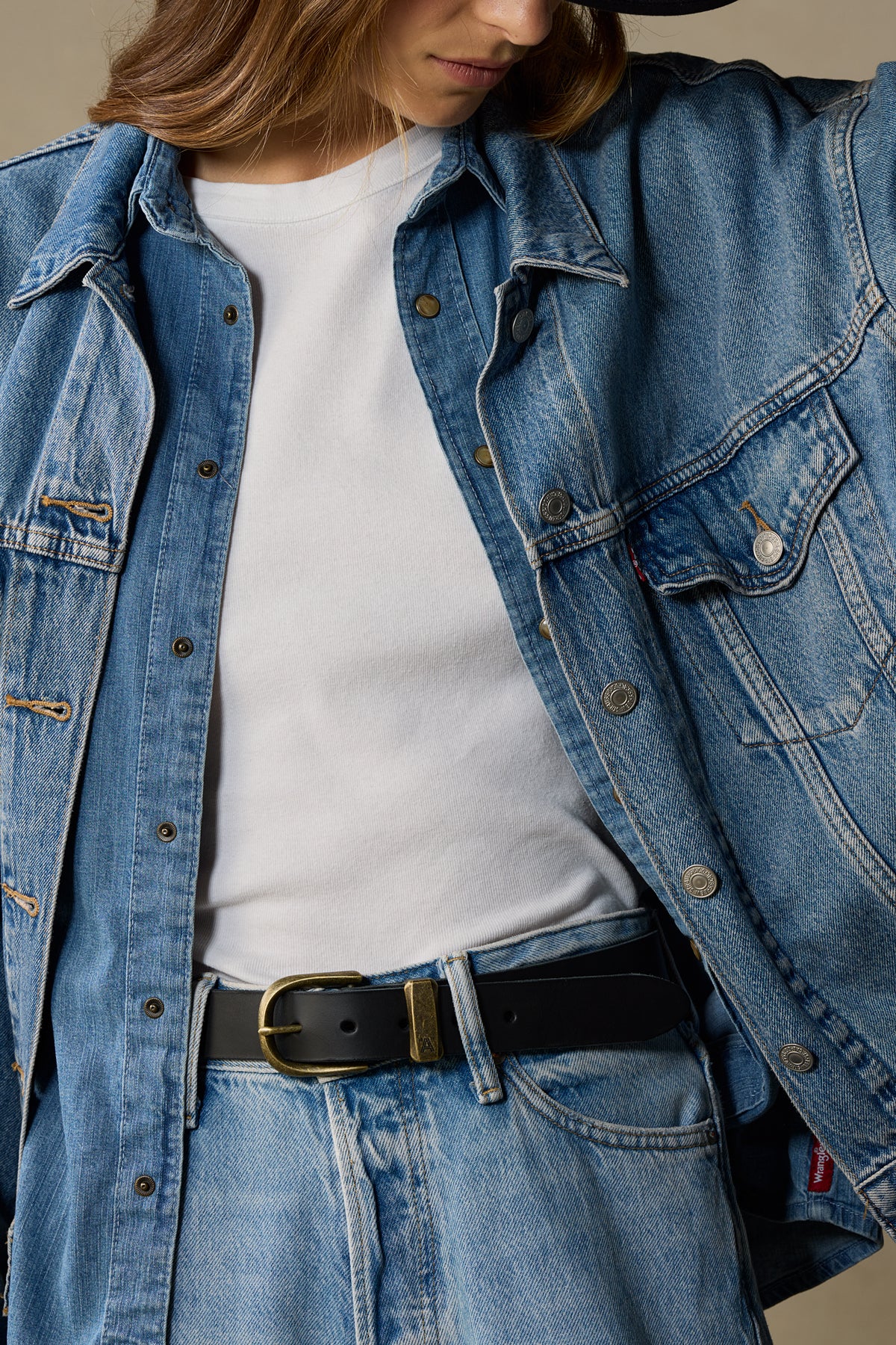 Black leather belt with brass buckle worn with denim jacket and jeans