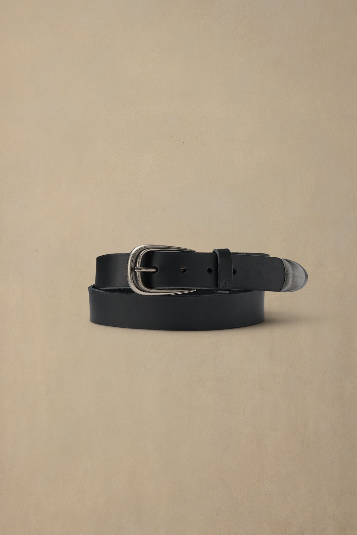 Black leather belt with silver buckle on beige background, coiled display