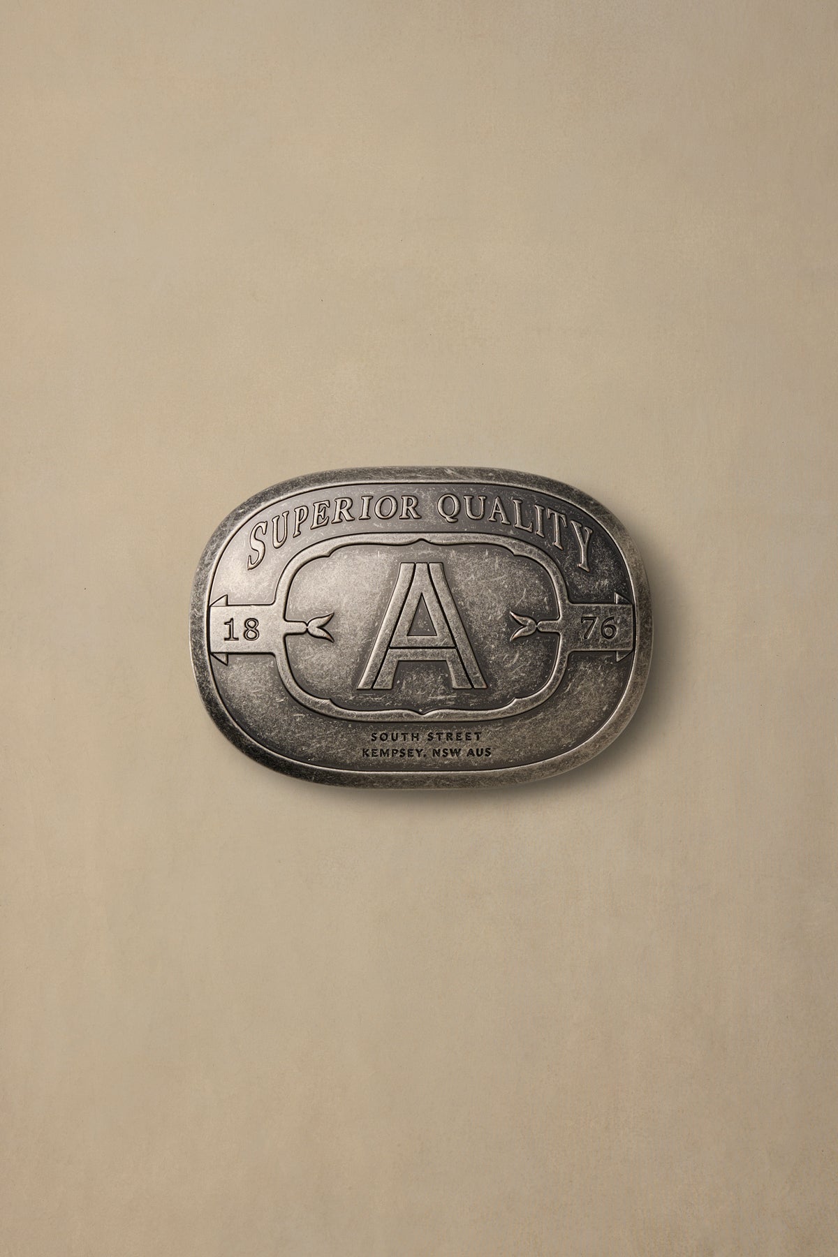 Vintage silver pewter belt buckle with ornate "A" design and "Superior Quality" text on cream background