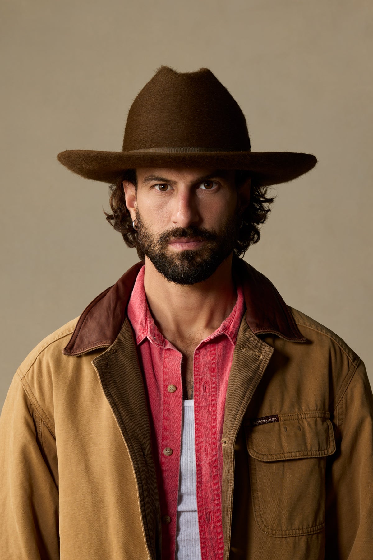 Brown felt cowboy hat worn by bearded man in tan jacket and red shirt
