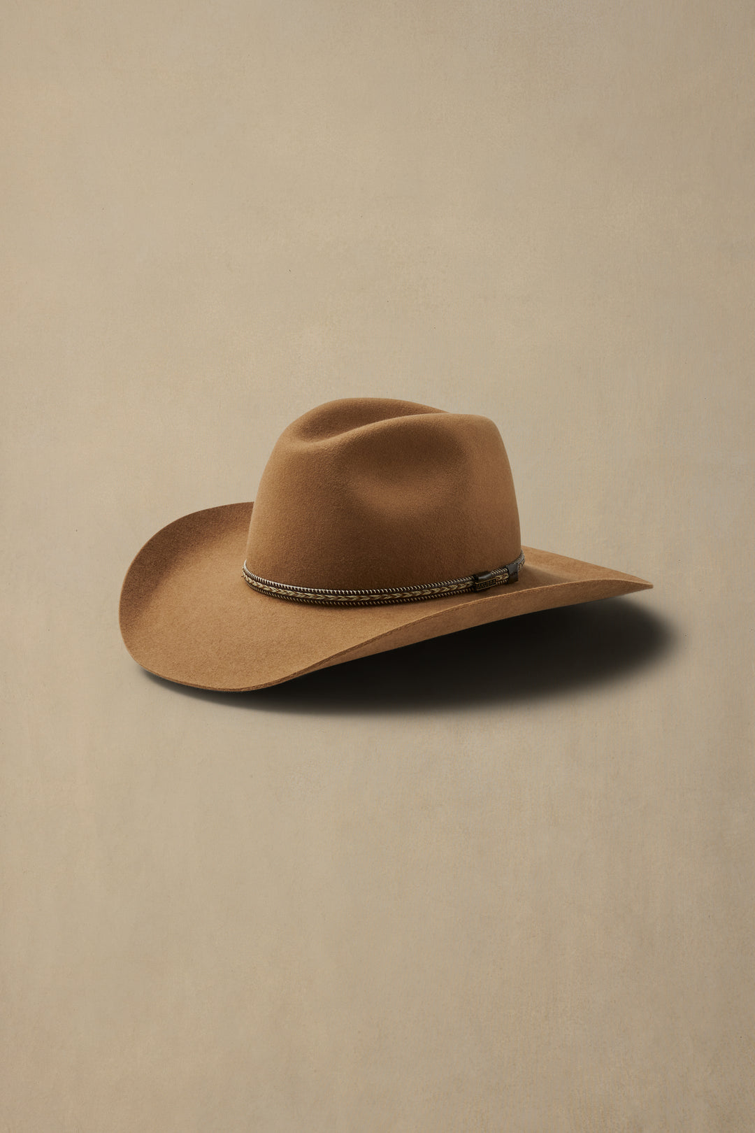 Tan fur felt cowboy hat with silver beaded band on neutral background