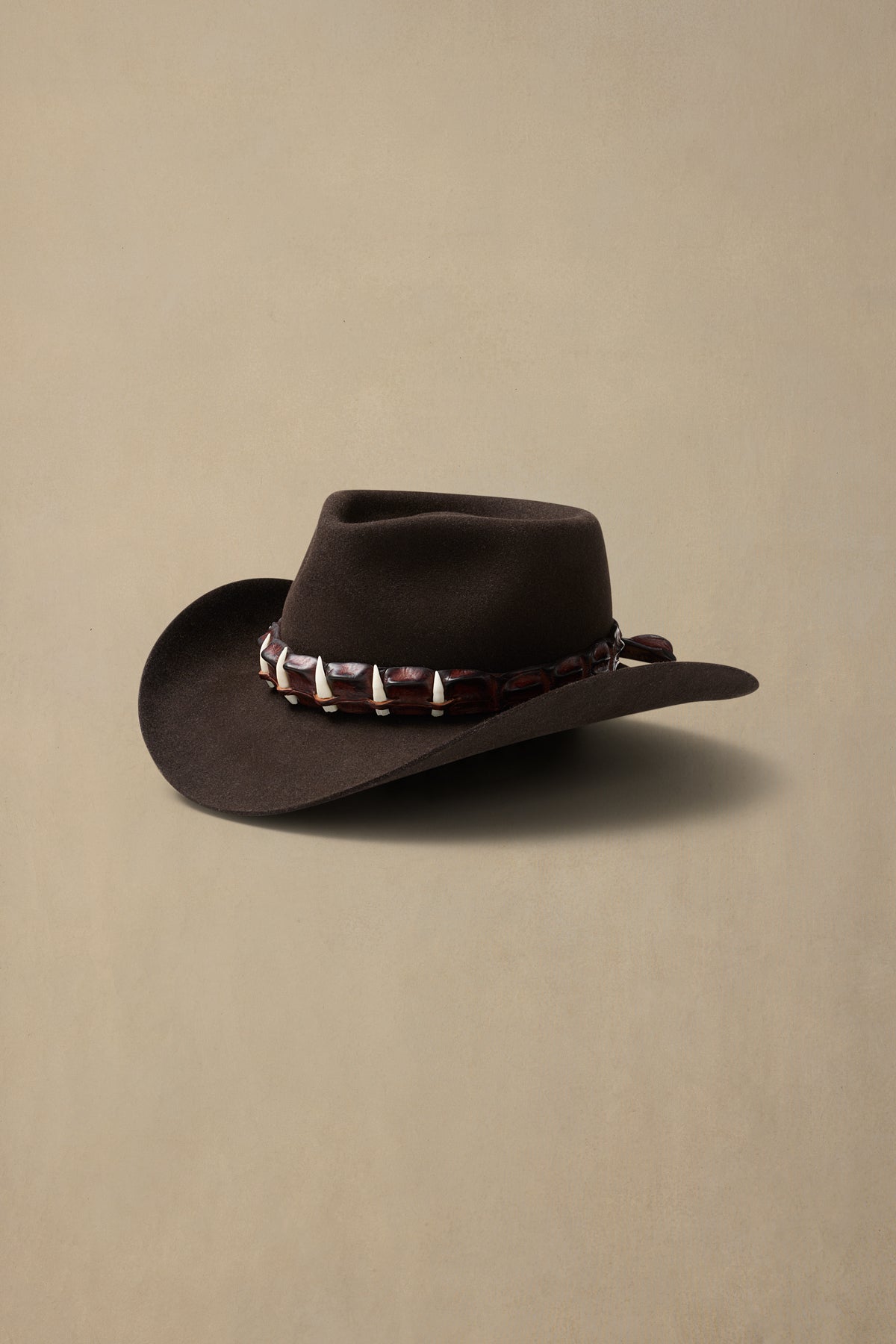 Dark brown rabbit fur cowboy hat with decorative studded band, displayed against neutral beige background