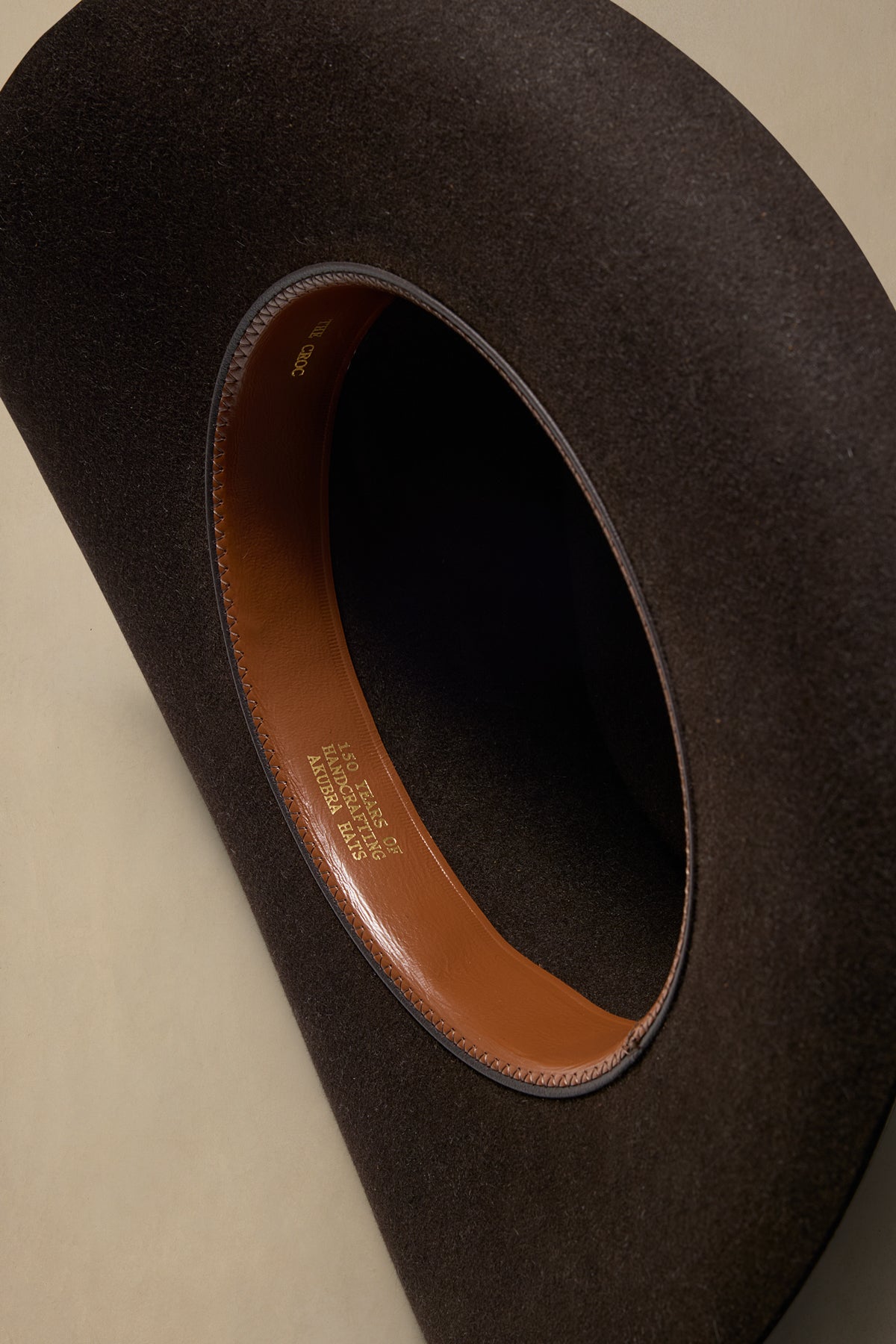 Dark brown rabbit fur felt hat with cognac leather sweatband, displayed at overhead angle showing interior detail