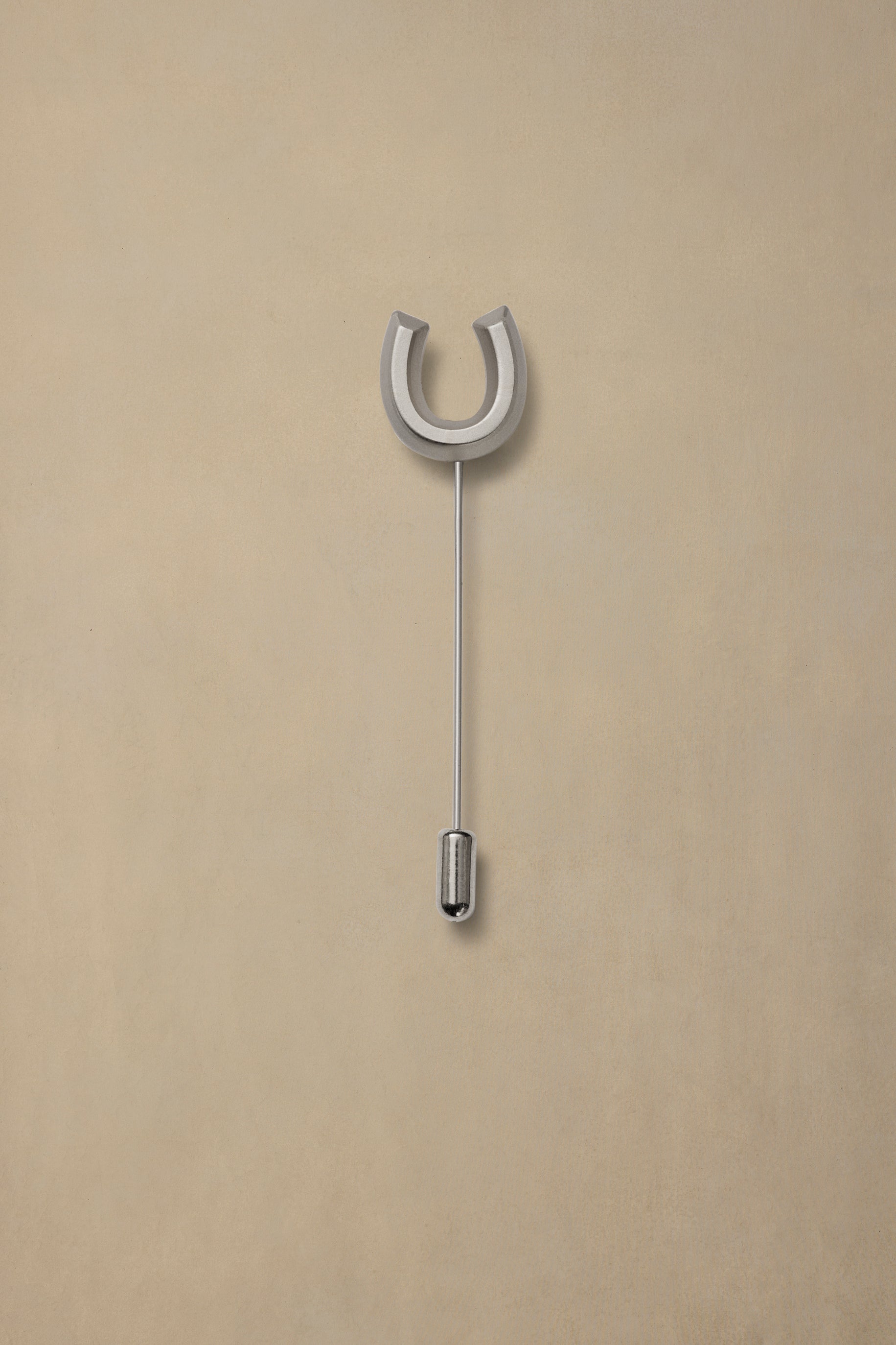 Lucky Pewter horseshoe pin with silver finish and thin stem on neutral beige background