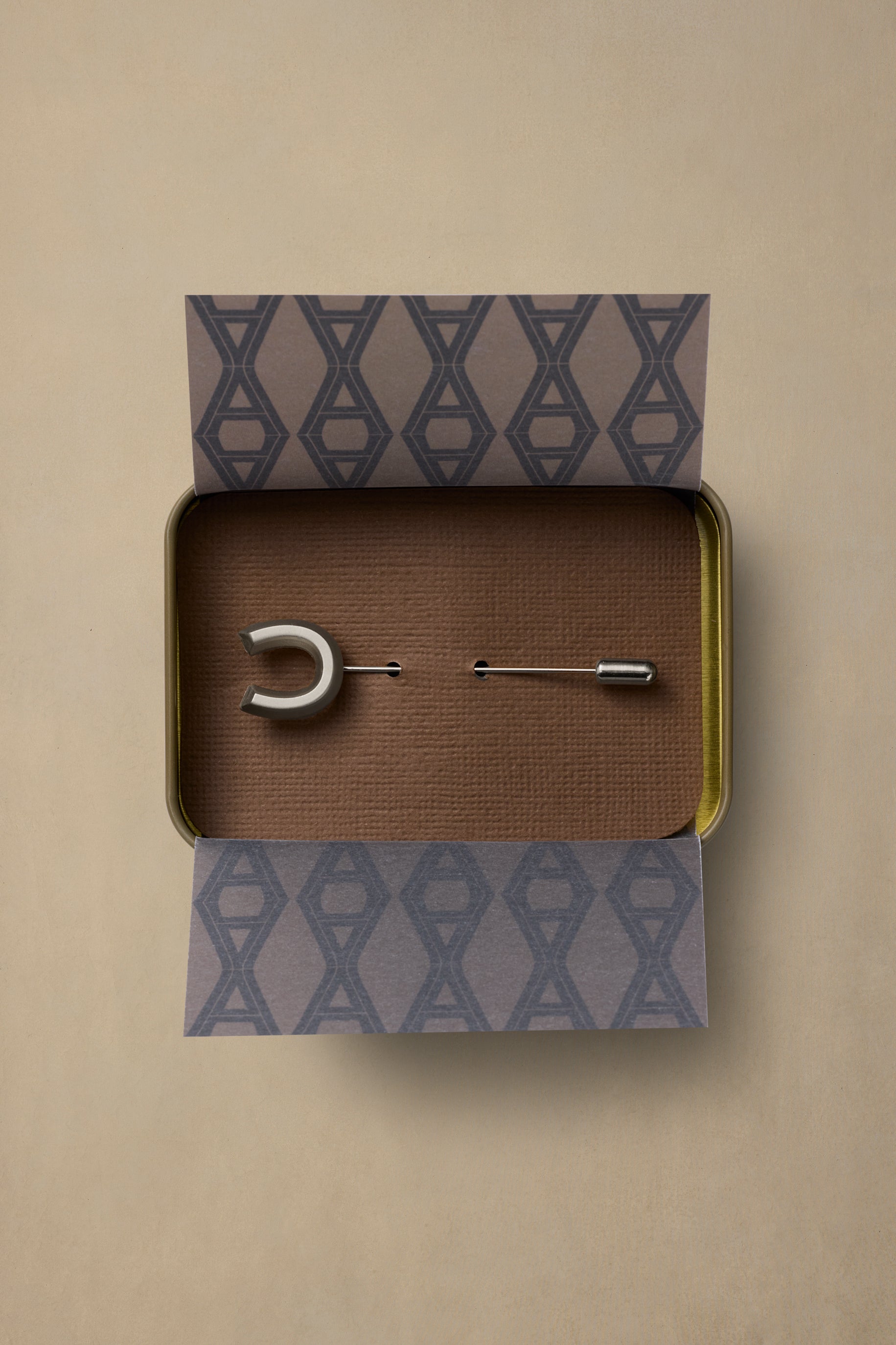 Lucky Pewter pin in crescent moon design displayed in branded box with geometric patterned tissue paper on neutral background