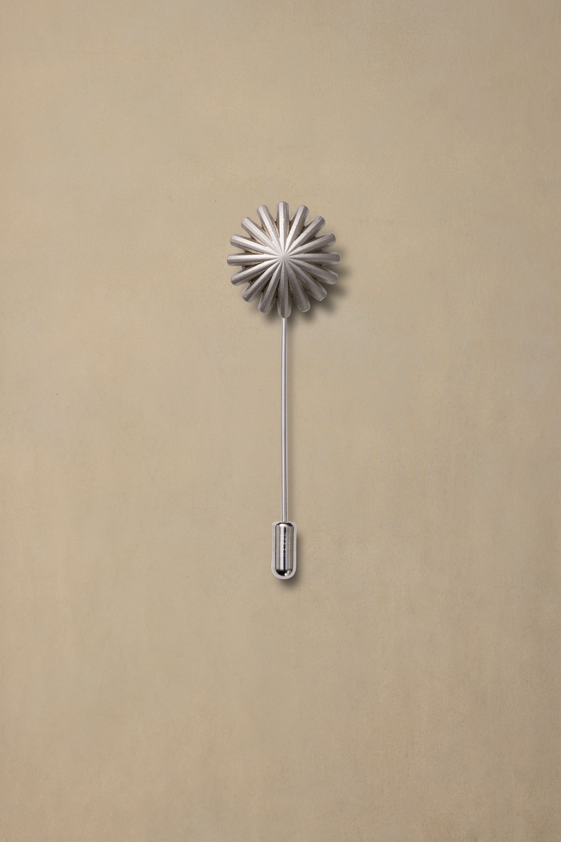 Pewter starburst pin with long stem on neutral beige background, minimalist product display