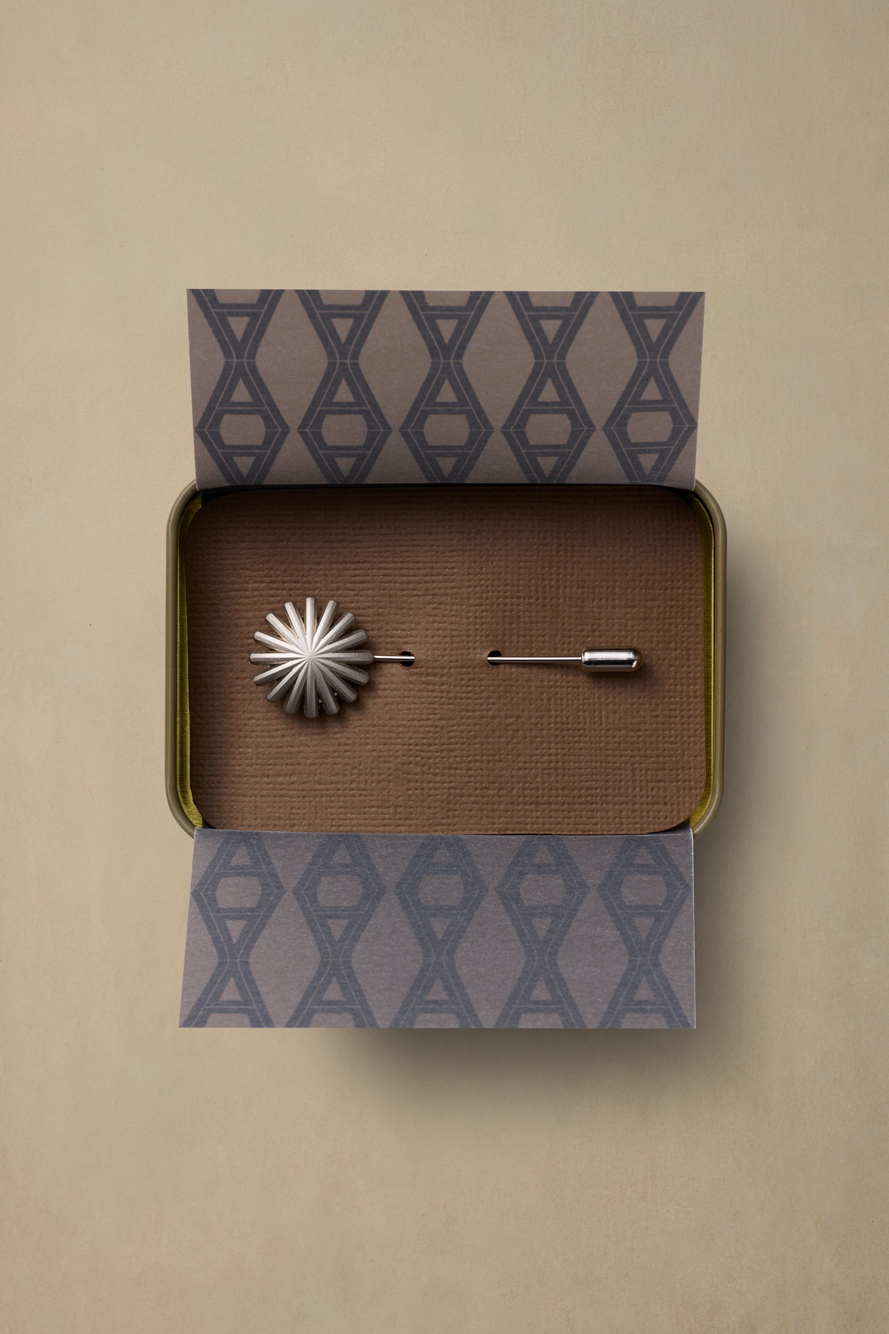 Hotrod Pewter pin with starburst design in open gift box with patterned tissue paper