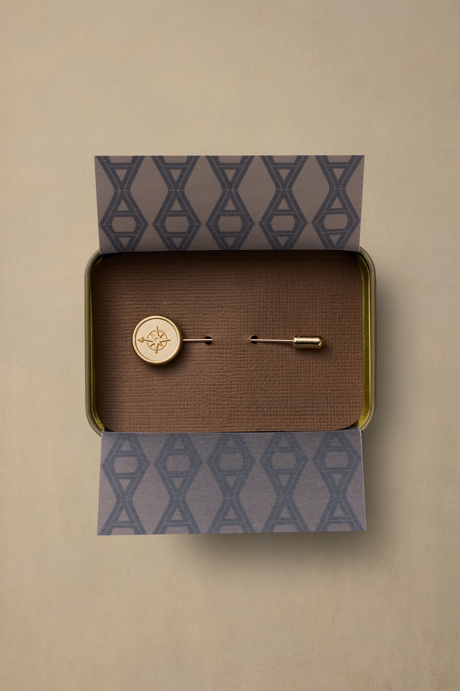 Brass compass rose pin with bar backing in branded gift box with patterned tissue paper