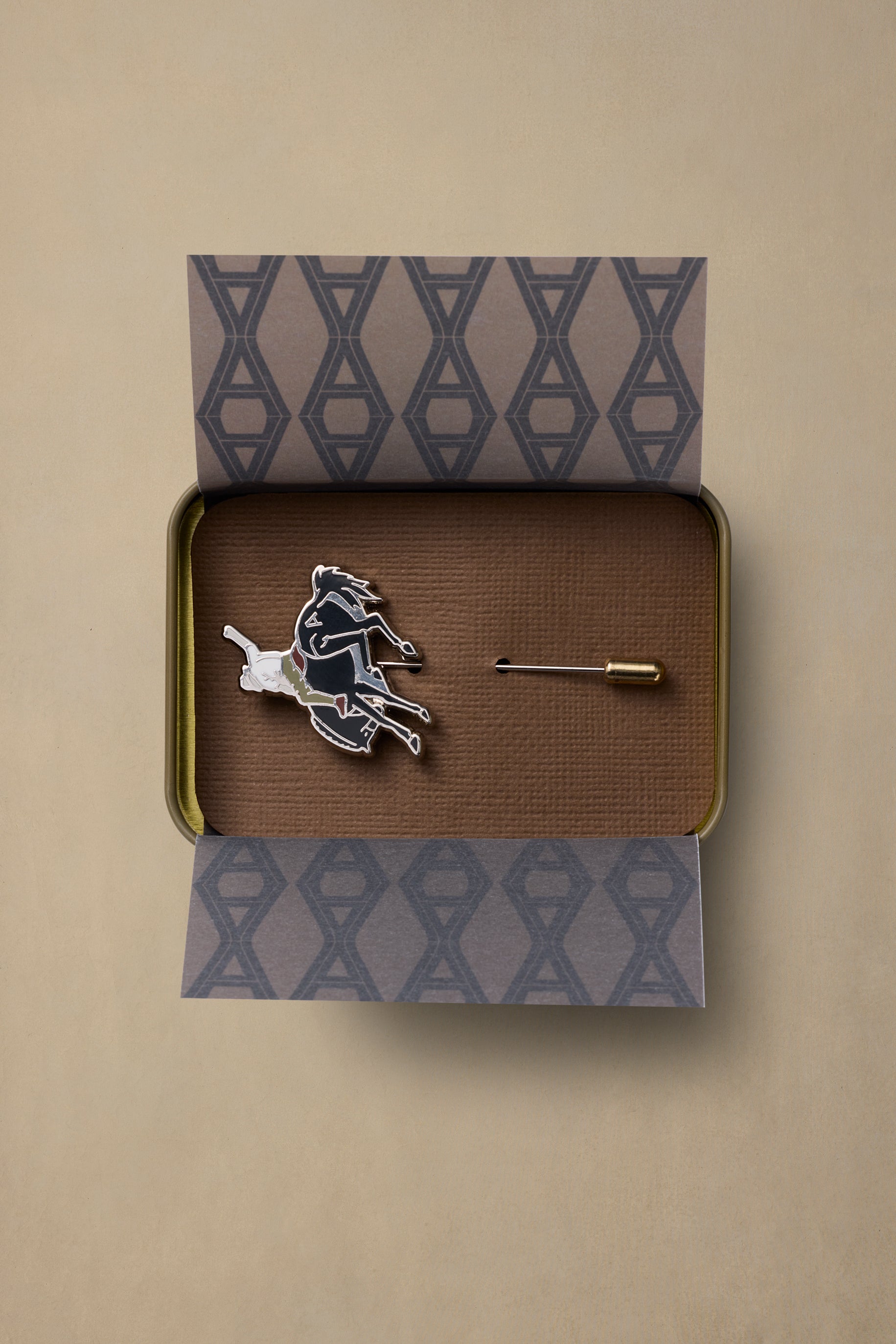 Bucking Bronc enamel pin with backing card in branded gift box on beige background