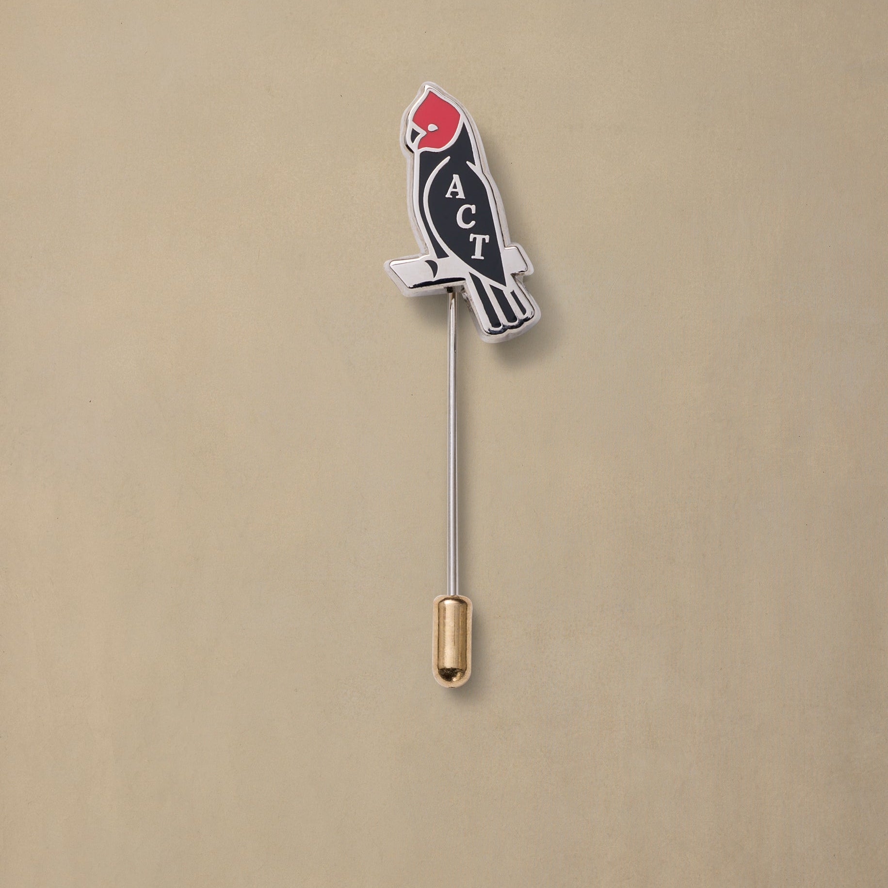 ACT State pin featuring red cardinal head on black body with gold clutch backing against tan background