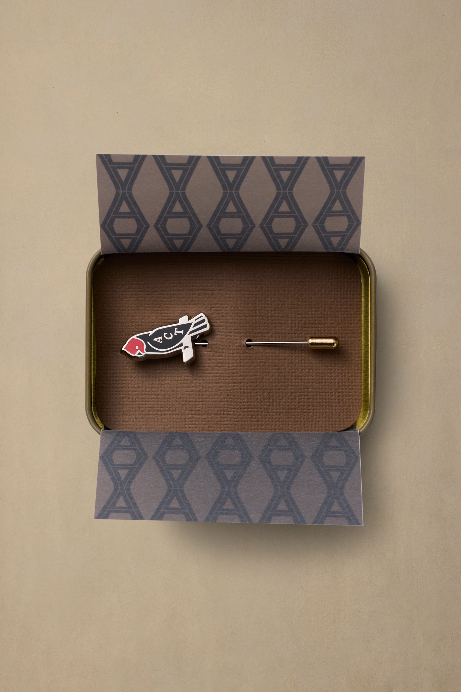 ACT State enamel pin featuring red and black fish design in gold-trimmed tin box with patterned packaging