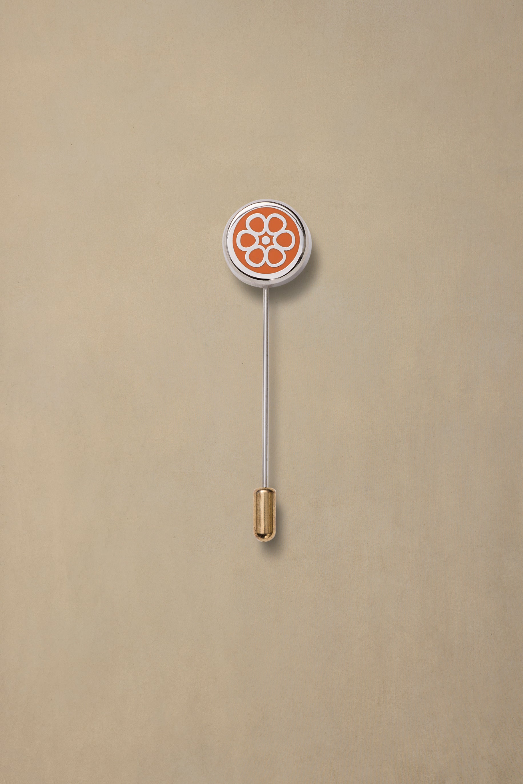 Orange and white NT State enamel pin with gold clutch back on beige background