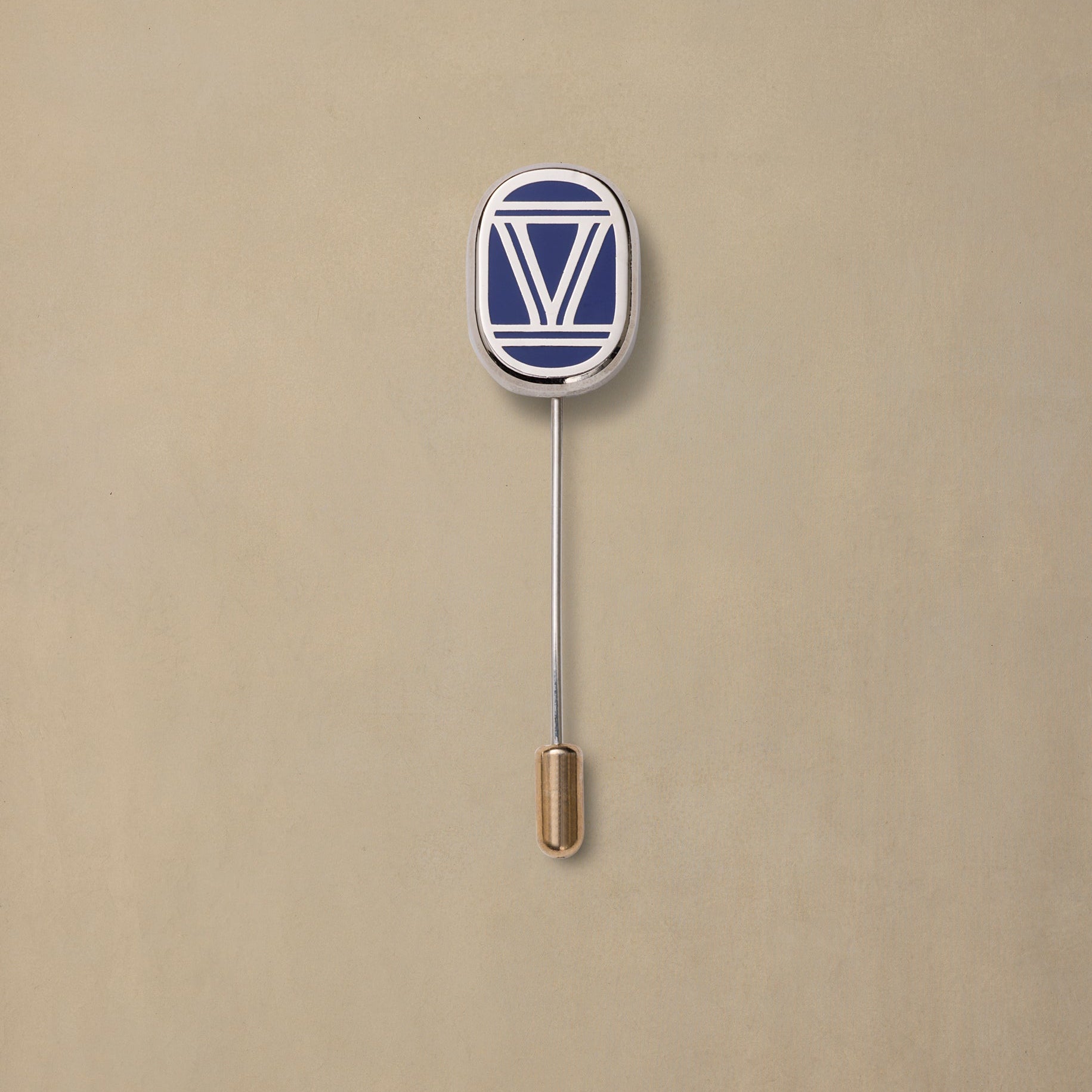 VIC State navy and white enamel pin with gold-toned metal backing on beige background