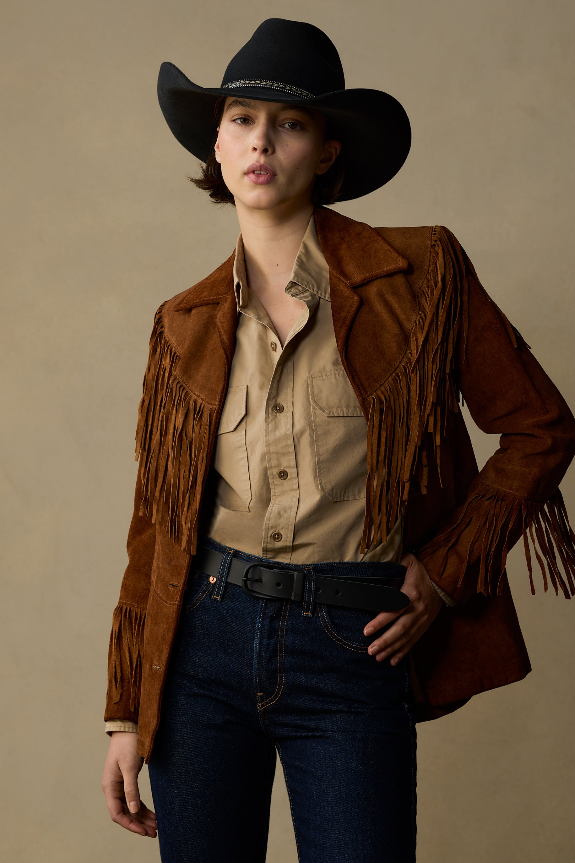 Black leather belt with gold buckle worn with fringe suede jacket and cowboy hat