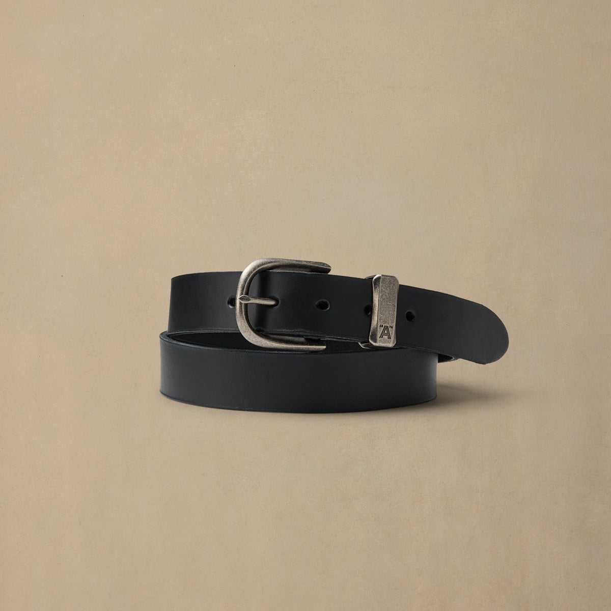 Black leather belt with silver buckle and metal loop detail on neutral background